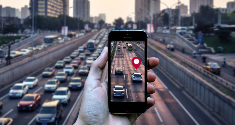 trojprúdová diaľnica s autami a v popredí ruka s mobilom a mobilnou aplikáciou